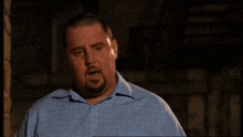a man with a beard and a blue shirt is making a funny face