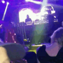 a group of people sitting in front of a stage with purple lights