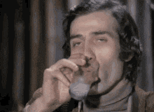 a man is drinking from a glass with his mouth open .