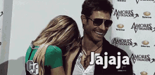 a man and woman are smiling in front of a wall that says amores verdaderos