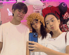 a group of people taking a selfie in front of a pink wall with a sign that says " happy "