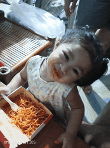 a little girl is eating spaghetti from a box with a fork