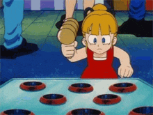 a little girl in a red dress is playing a game with a hammer .