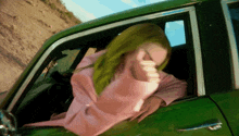 a woman with green hair is sticking her head out the window of a green car
