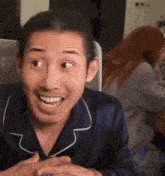 a man in a blue shirt is smiling with a woman behind him