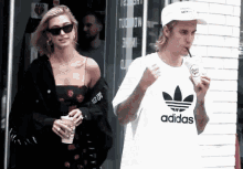 a man wearing an adidas t-shirt is drinking through a straw