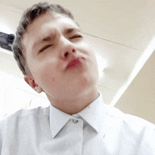 a young man in a white shirt is making a funny face with his eyes closed