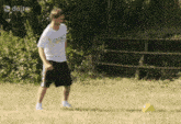 a man in a white shirt with the olympics on it is kicking a ball