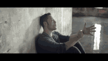 a man leaning against a wall with his arms outstretched .