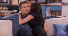 a man and woman are sitting on a couch and the woman is kissing the man