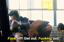 a man sitting on a couch with the words " fuck off get out fucking out "