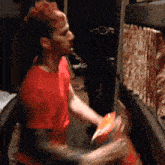a man in a red shirt is playing a guitar