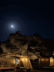 a full moon is visible in the night sky above a camping area