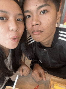 a boy and a girl are sitting at a table with a box of mcdonald 's french fries in front of them