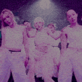 a group of women are dancing on a stage in purple light