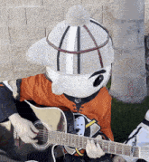a mascot is playing a guitar and wearing an orange shirt