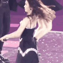 a woman in a black dress is dancing on stage .