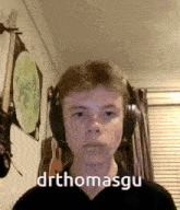 a young man wearing headphones with the name drthomasgu written on his face