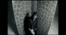a man in a suit and tie stands in front of a wall