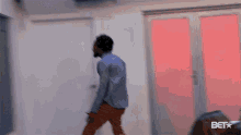 a man in a blue shirt is dancing in a room with a bet logo on the bottom