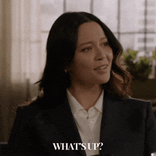 a woman in a suit and white shirt is asking what 's up