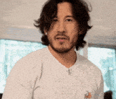 a man with a beard is wearing a white t-shirt