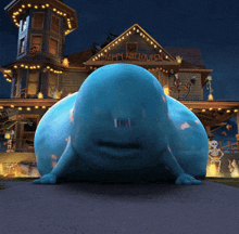 a blue monster is standing in front of a haunted house at night