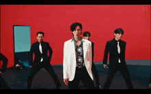 a group of men in suits and ties are dancing in front of a red wall ..