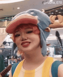 a woman wearing a blue hat with a pink brim is smiling for the camera