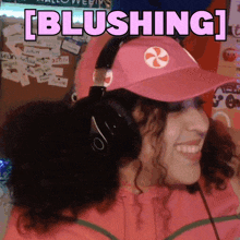 a woman wearing headphones and a pink hat with the word blushing written on it