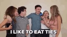 a group of people are standing around a man holding a microphone with the words " i like to eat ties " on the bottom