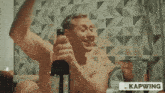 a shirtless man in a bathtub is holding a bottle of wine with the caption kapwing