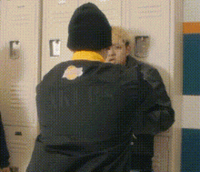 two men are standing in front of lockers in a locker room .
