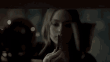 a woman is holding a knife in her hand and looking at herself in a mirror .