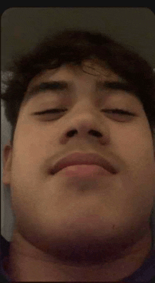 a close up of a man 's face with his eyes closed and a beard .