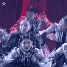 a group of people are dancing in front of a red curtain with a white star in the corner