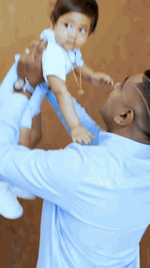 a man in a blue shirt is holding a baby