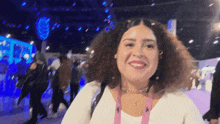 a woman with curly hair wearing a white shirt and a pink lanyard around her neck