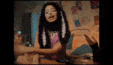 a woman with feathers in her hair is sitting on a bed in a room .