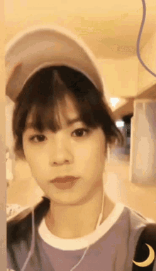 a woman wearing a baseball cap and a purple shirt looks at the camera