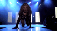 a woman is crawling on the floor on a stage in front of a blue light .