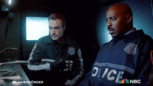 two police officers are standing next to each other in a dark room with a nbc logo in the corner