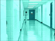 a man is walking down a hallway with a red door in the background