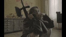 a person holding a gun in front of a wall that has the word hit painted on it