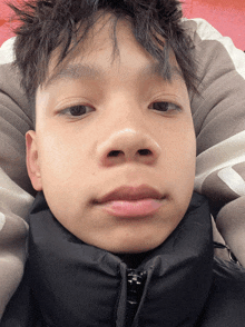a close up of a young man 's face with a black jacket around his neck