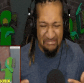 a man with dreadlocks is wearing headphones and making a funny face in front of a microphone .