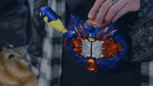a person with a ring on their finger holds a blue and orange toy