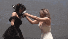 a woman in a white dress stands next to a woman in a black dress on a stage