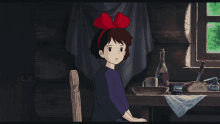 a girl with a red bow in her hair sits at a table