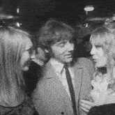 a man in a suit talks to two women